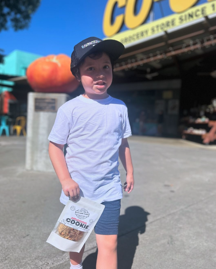 Lucian holding an Applelicious Cookie pouch outside a grocery store
